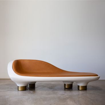 Sculptural modern lounge chair featuring a sleek design with a leather seat and brass accents, showcased in gallery setting.