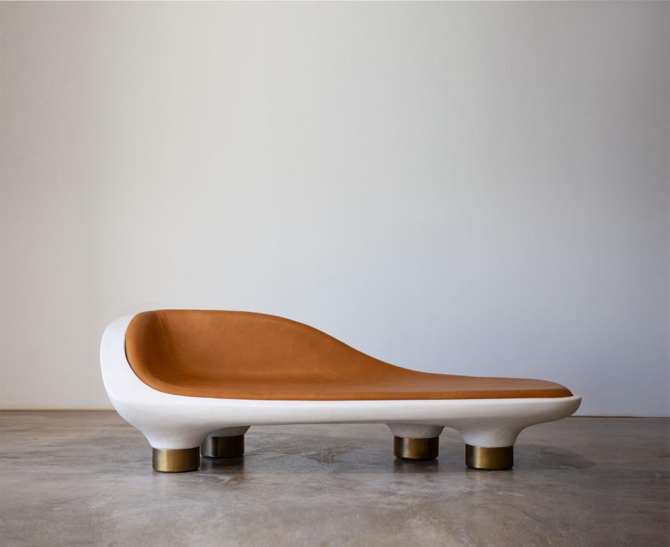 Sculptural modern lounge chair featuring a sleek design with a leather seat and brass accents, showcased in gallery setting.