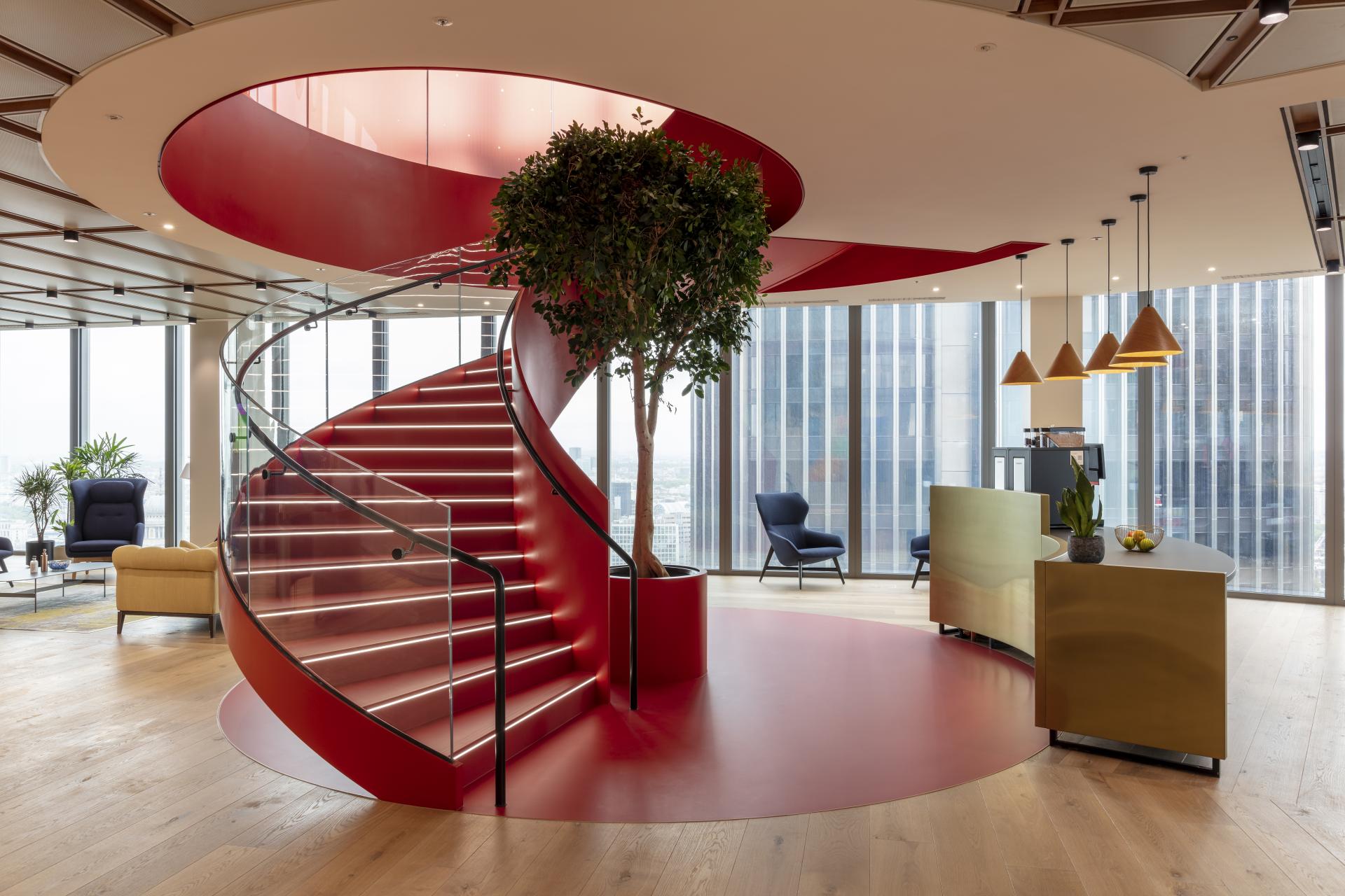 Modern office interior featuring a red spiral staircase, greenery, and stylish seating at 22 Bishopsgate, London.