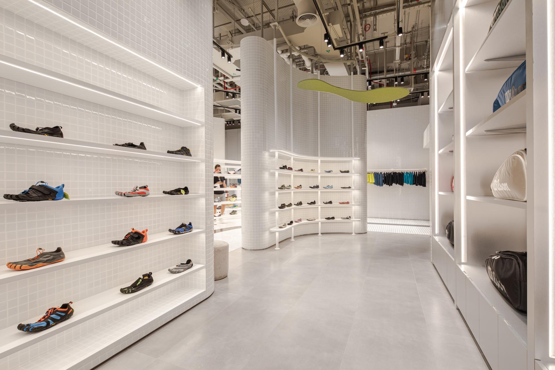 Modern concept store interior showcasing a variety of vibrant activewear shoes displayed on sleek white shelves.