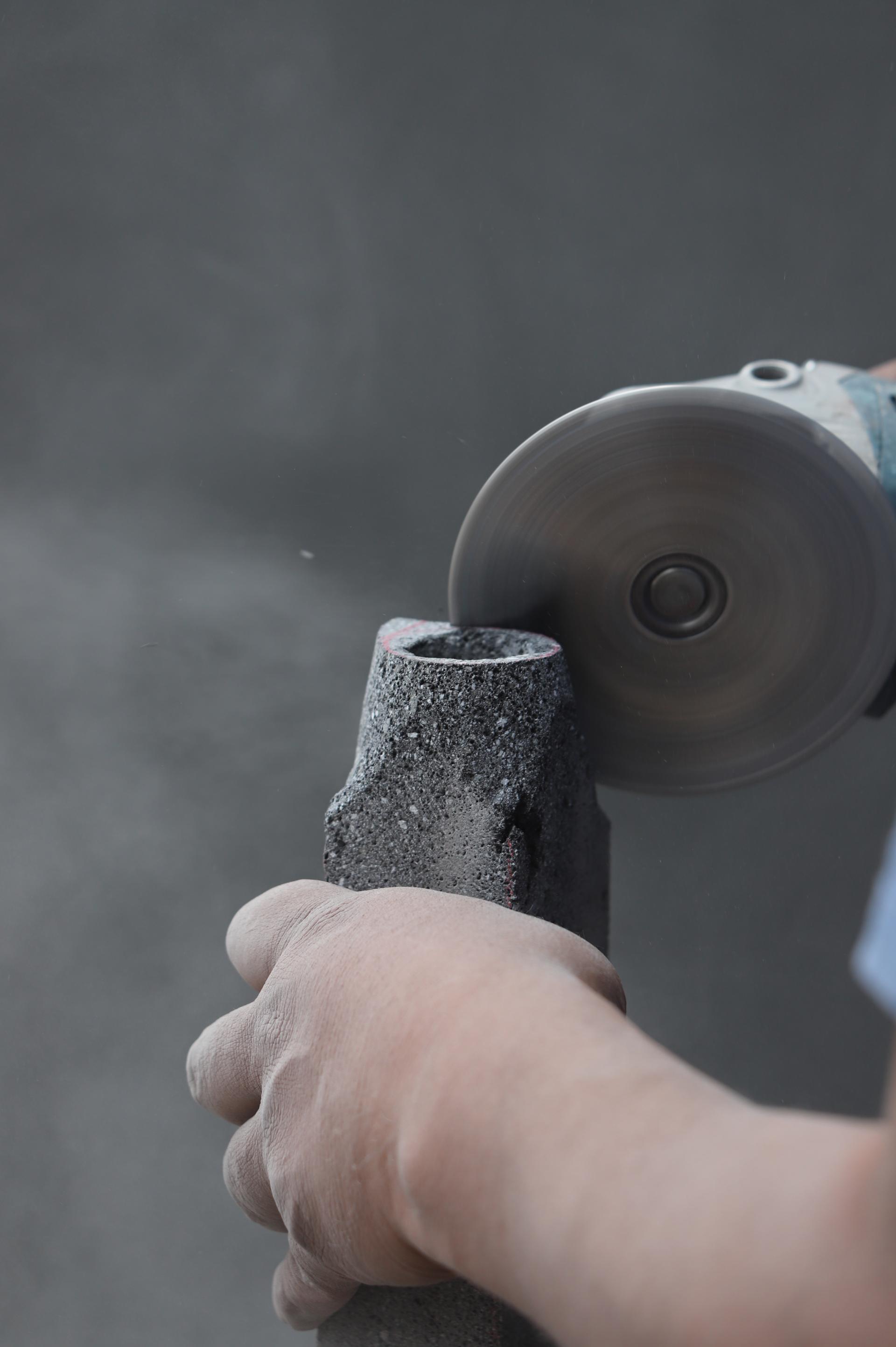 Craftsman shaping volcanic stone with a circular saw, creating unique finishes for studio davidpompa's Meta collection.