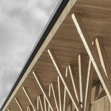 Elegant wooden colonnade of Icaro Hotel showcasing contemporary architecture against a dramatic Dolomite mountain backdrop.