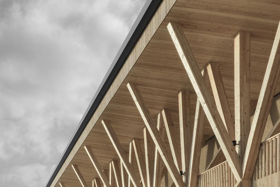 Elegant wooden colonnade of Icaro Hotel showcasing contemporary architecture against a dramatic Dolomite mountain backdrop.