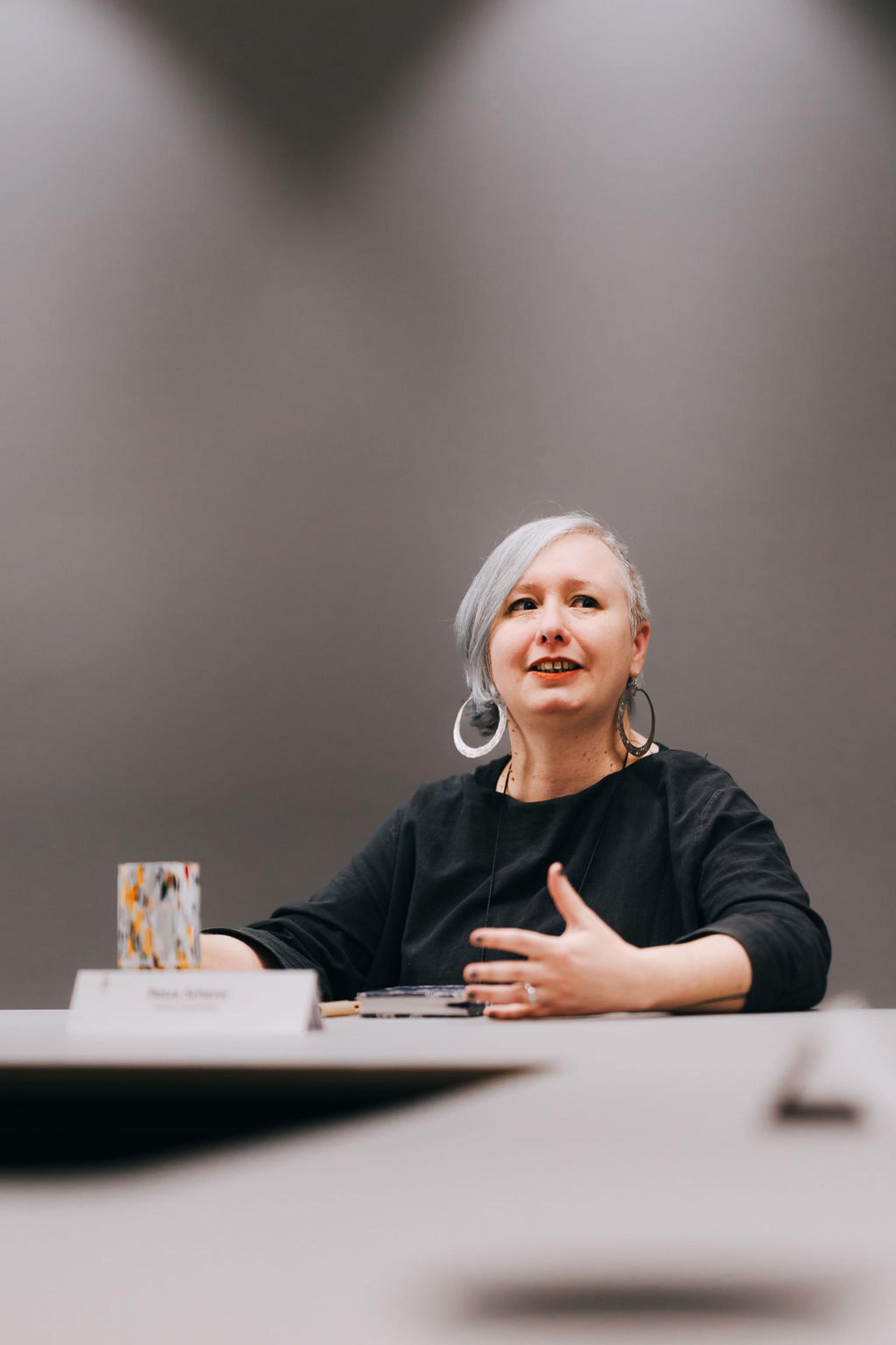 Woman discussing biomaterials at a roundtable, highlighting innovative sustainability practices in design and materials selection.