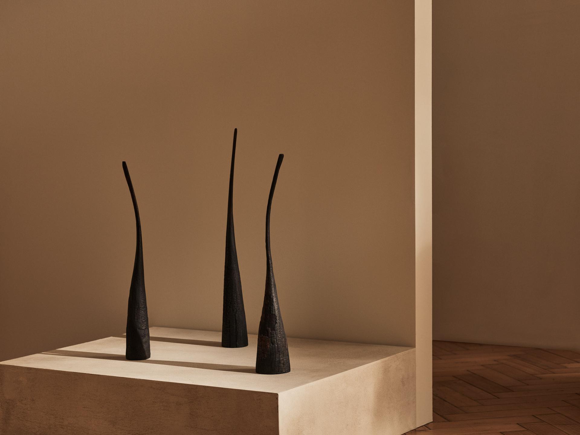 Elegant black sculptures displayed on a light-colored pedestal in a minimalist contemporary art setting, highlighting collectable craft.