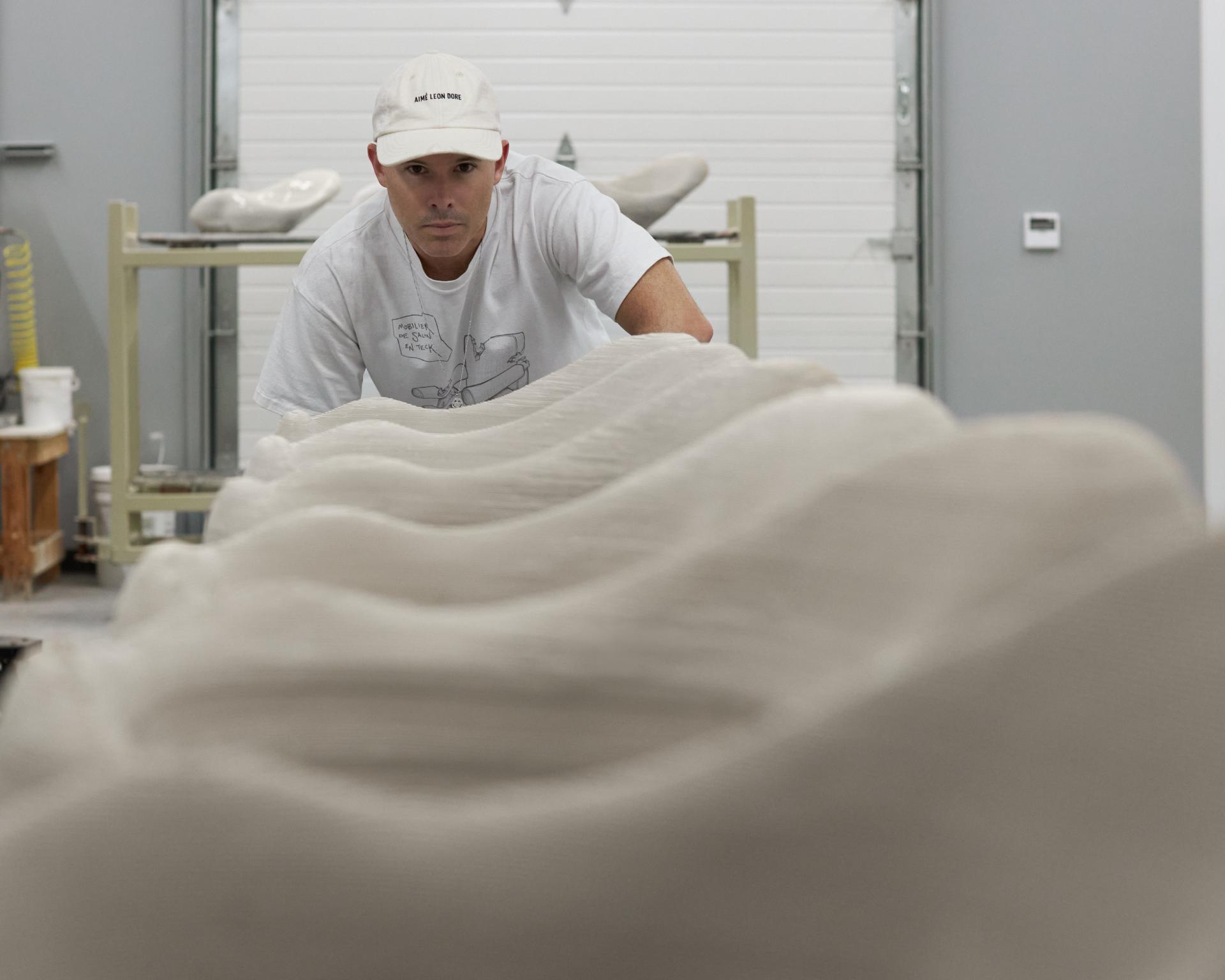 Craftsman focused on shaping a wave-like 3D-printed sink in a modern workshop during the Kohler x Daniel Arsham collaboration.