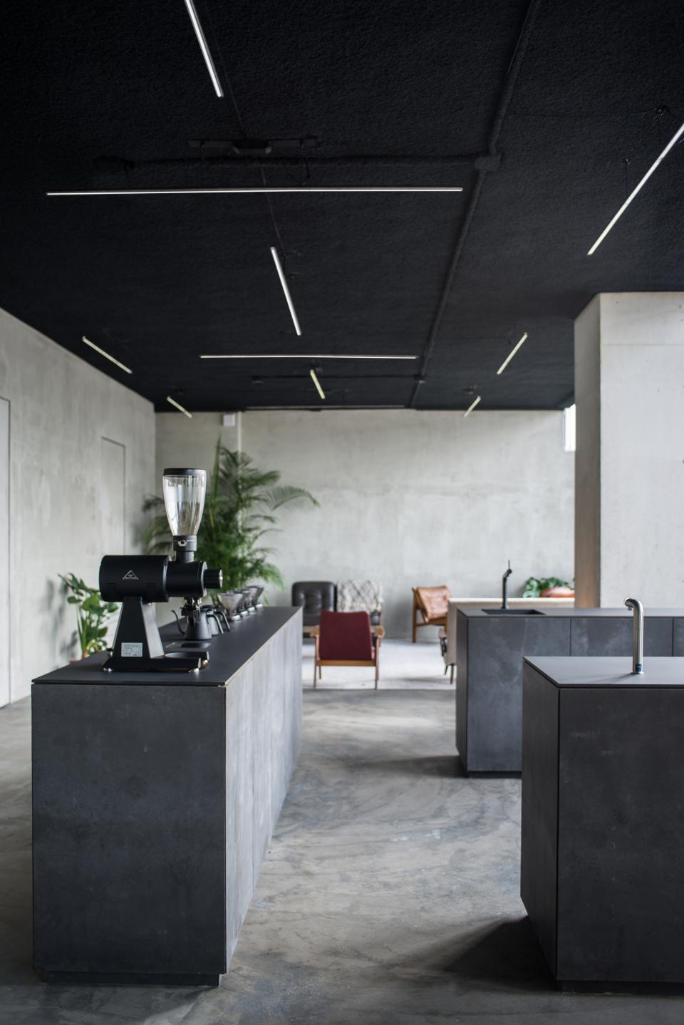 Minimalist interior design featuring concrete elements, industrial fixtures, and sleek lighting at HOP's Public Space in Amsterdam.