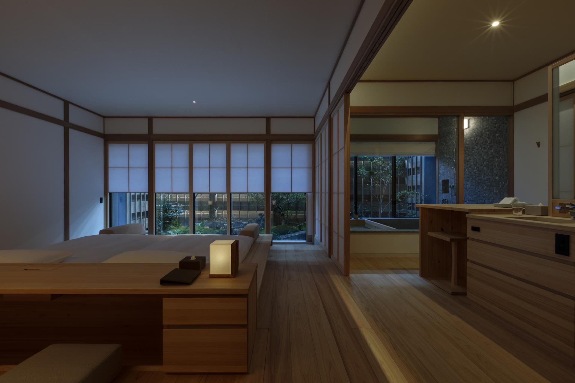 Modern Japanese ryokan interior featuring wooden furnishings, ambient lighting, and a tranquil garden view.