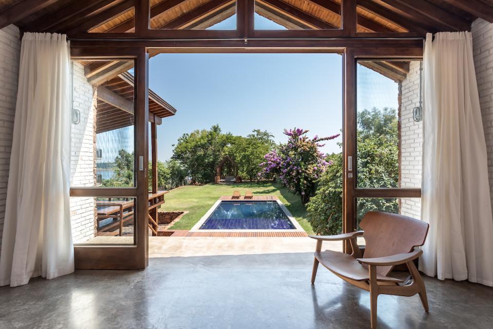Stylish interior view of The Lake House, showcasing modern design, a pool, and lush gardens in Brazil.
