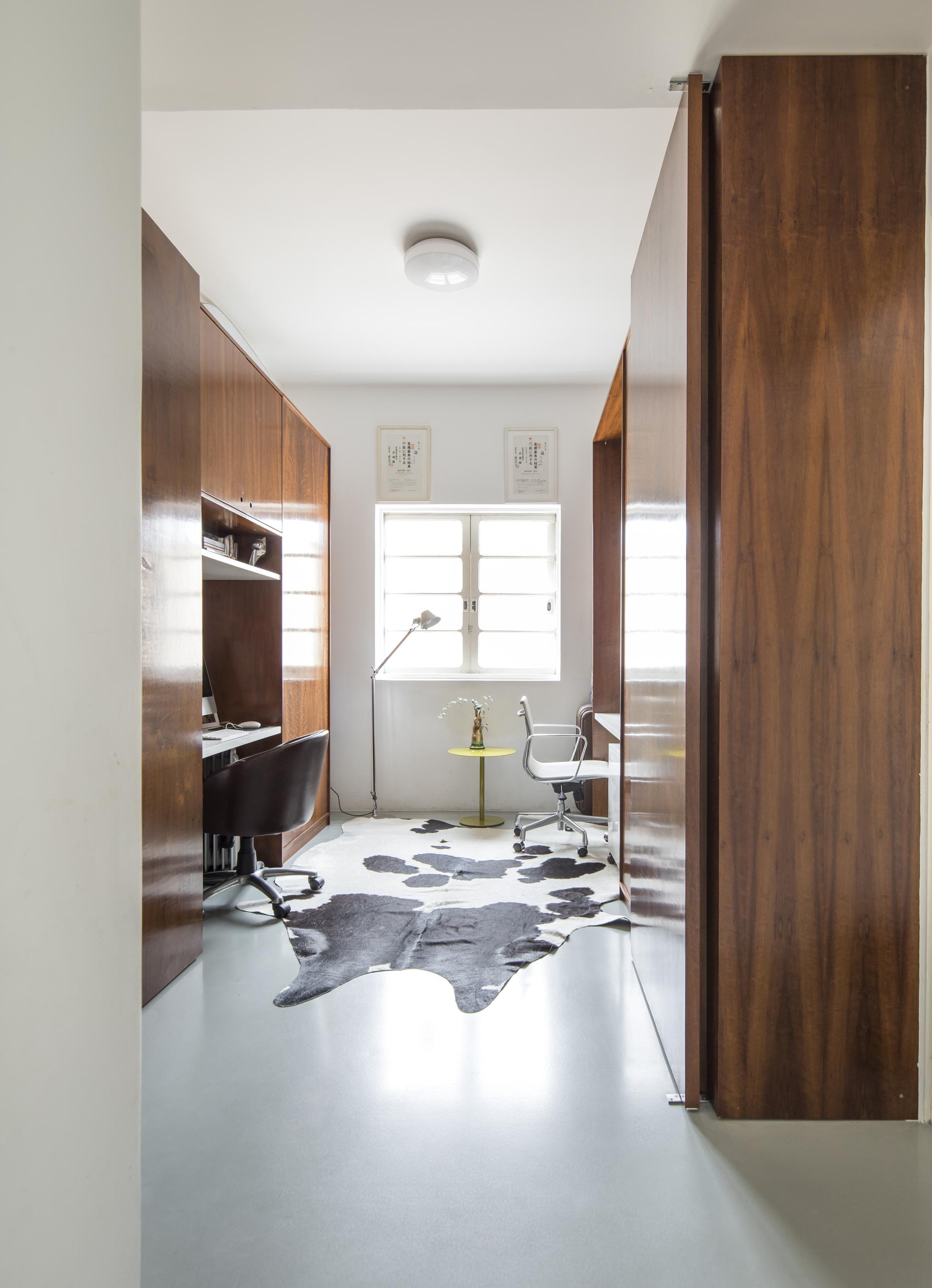 Stylish mid-century office space featuring wood accents, modern furniture, and a cowhide rug in a renovated São Paulo apartment.