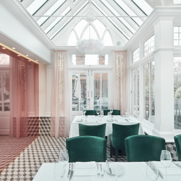 Elegant interior of Bluebells Restaurant in Ascot, featuring luxurious green velvet chairs and bright, airy decor.