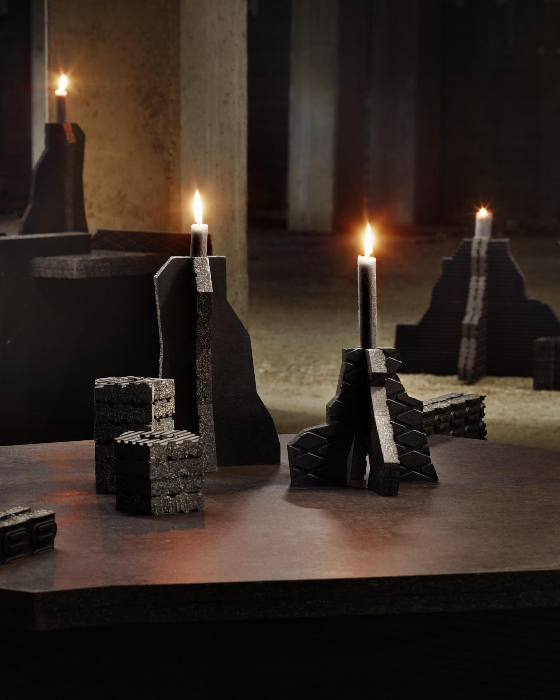 Circular furniture and candle holders made from recycled rubber in a dimly lit industrial setting.