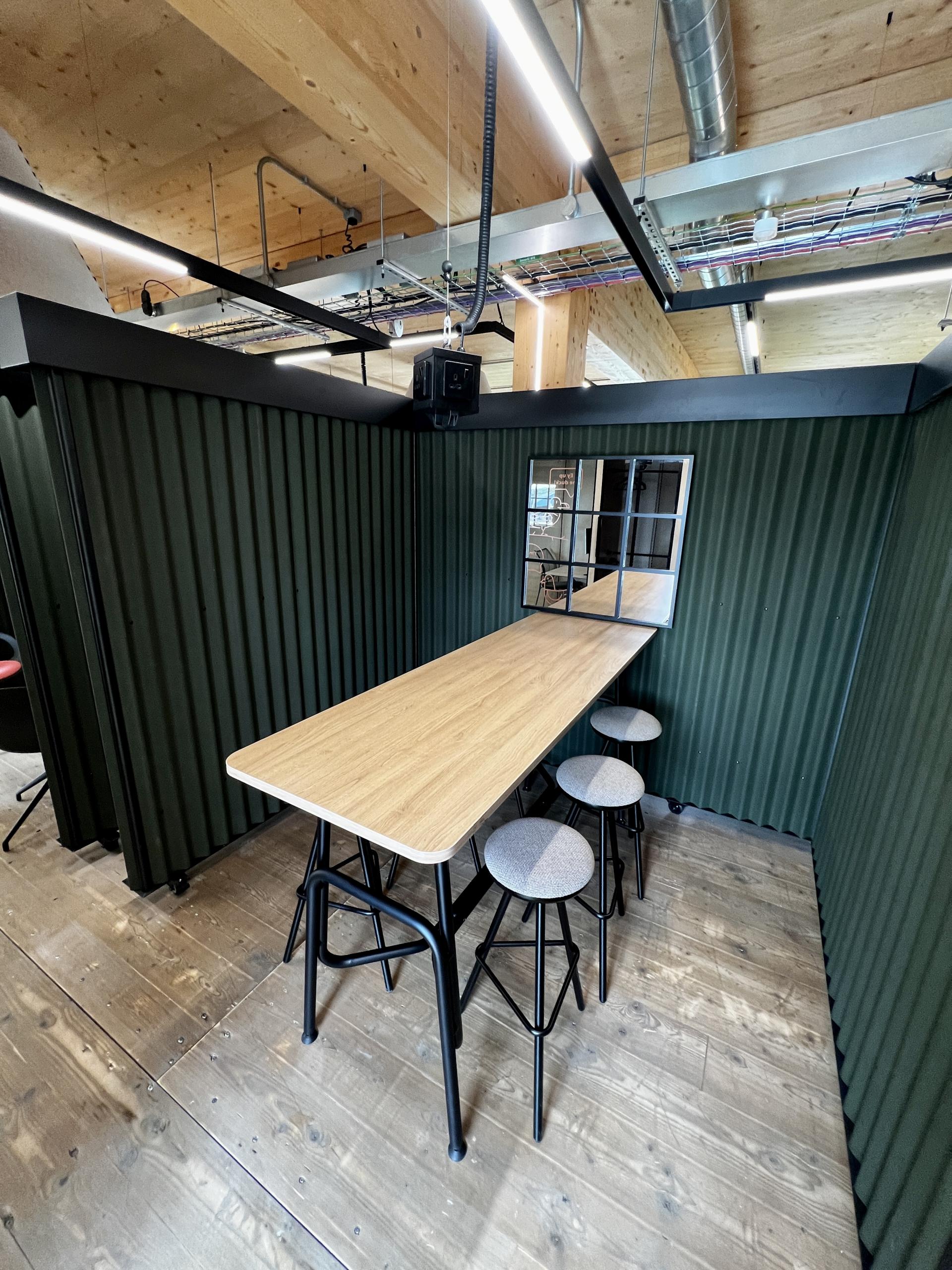 Modern workspace featuring a wooden table and stools in an environmentally sustainable design, highlighting Leeds’ net zero carbon initiative.