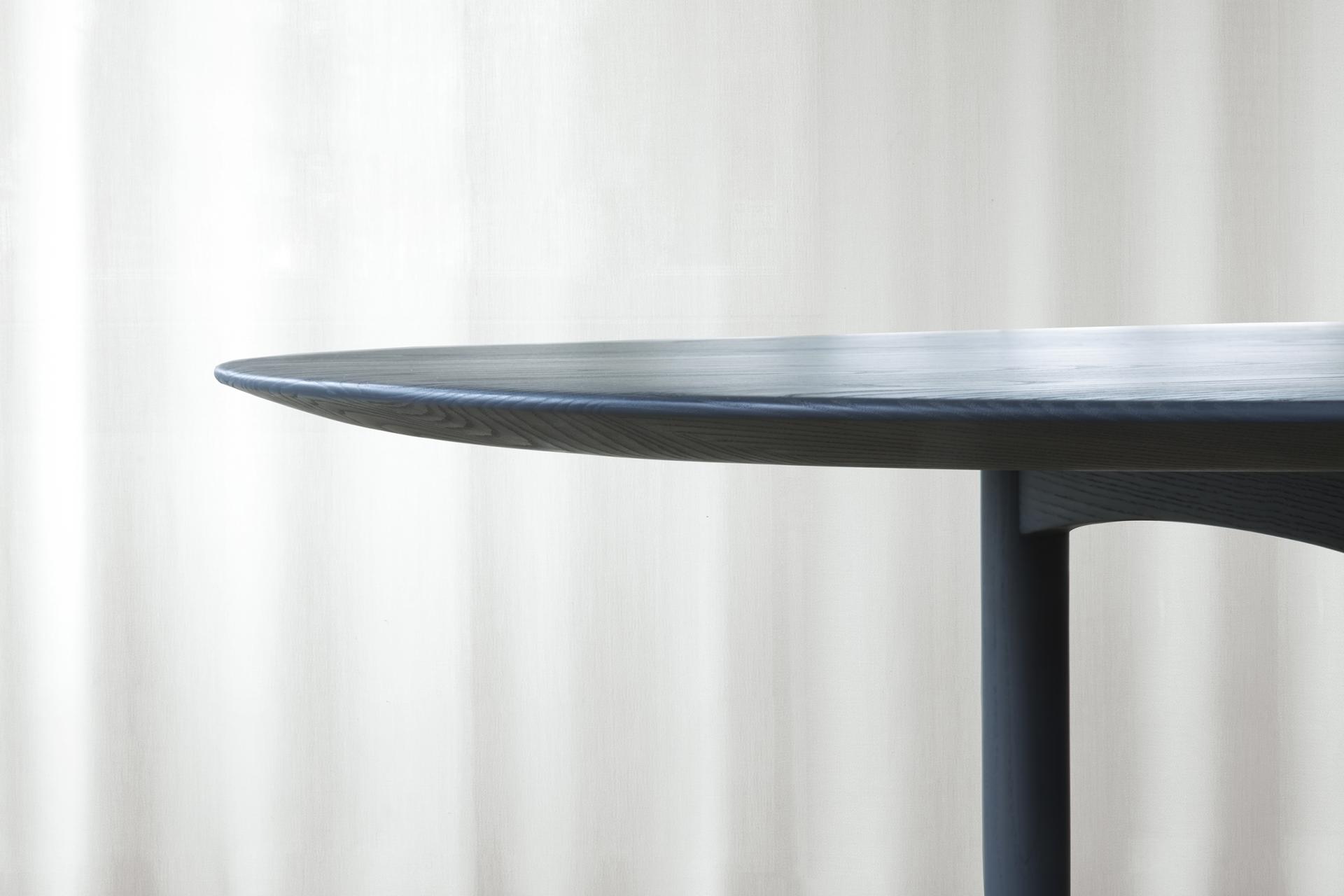 Elegant round dining table from Brdr. Krüger's JARI collection, featuring a smooth, dark wood finish against a light backdrop.