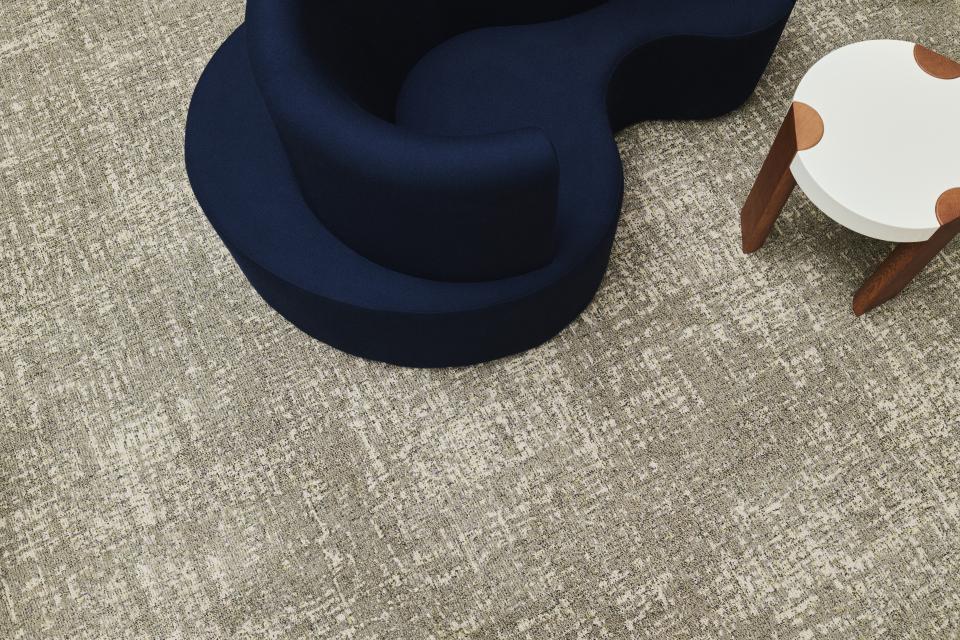 Stylish blue chair atop a textured beige carpet, showcasing Ege's ReForm Memory collection designed for wellbeing.