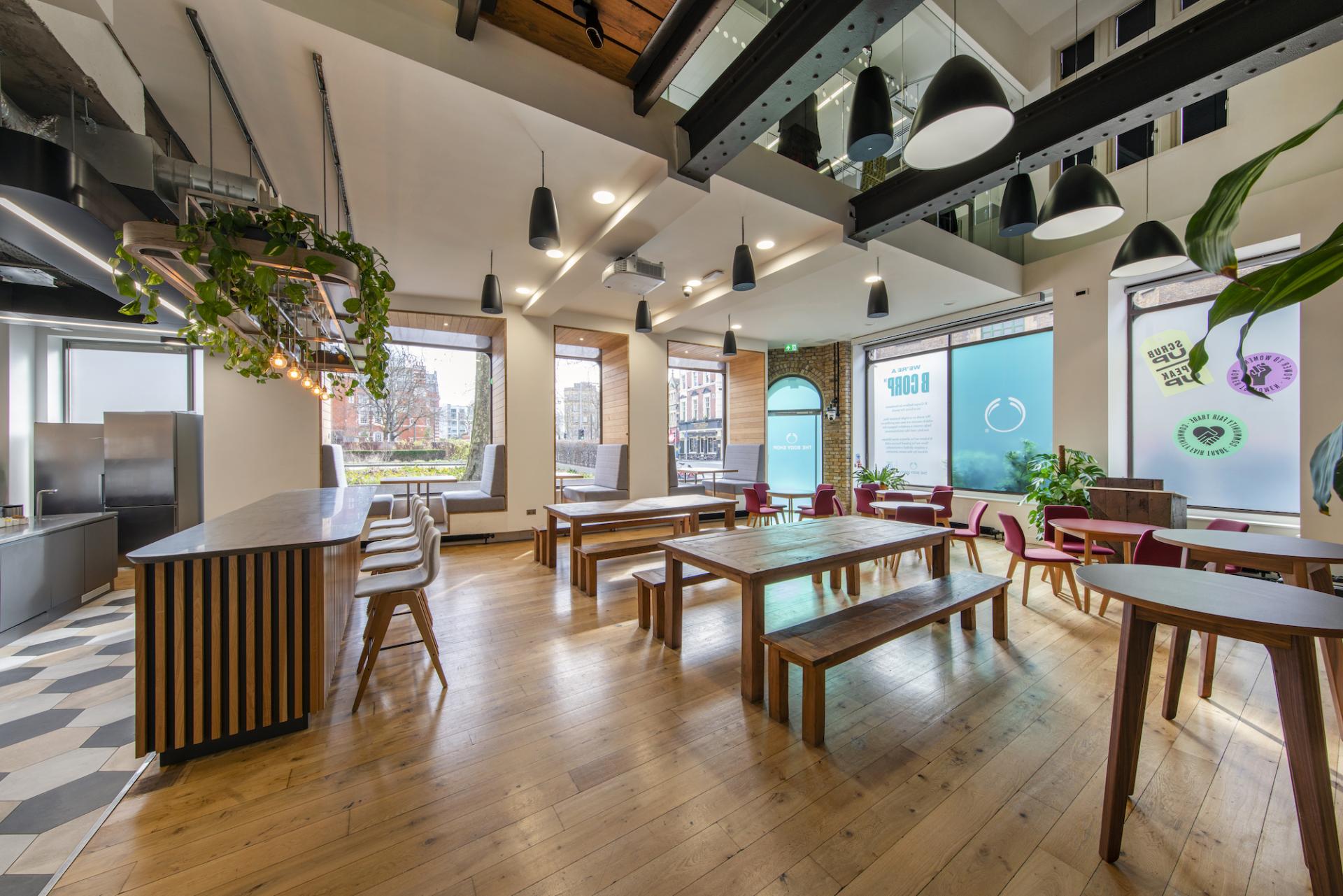 Stylish modern workplace interior featuring wooden furniture, plants, and large windows promoting a collaborative design environment.