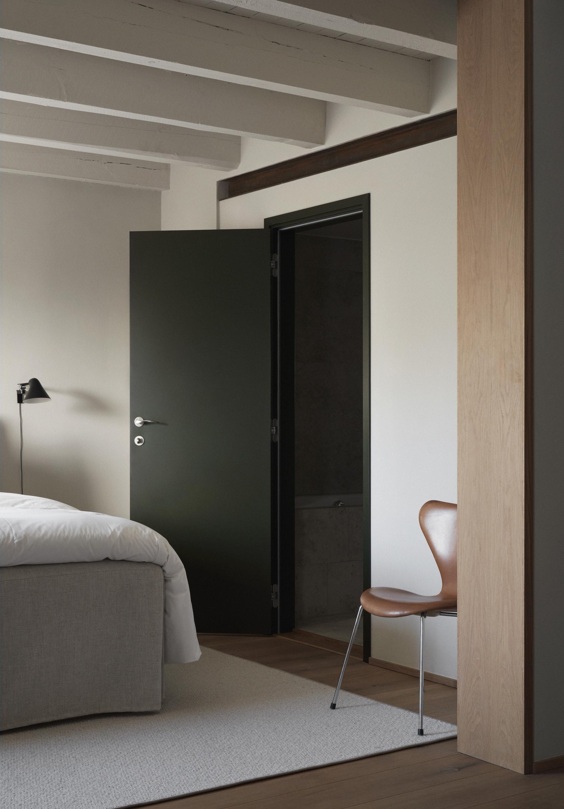 Modern Swedish bedroom featuring Arne Jacobsen's chair, natural light, earthy tones, and minimalist design elements.