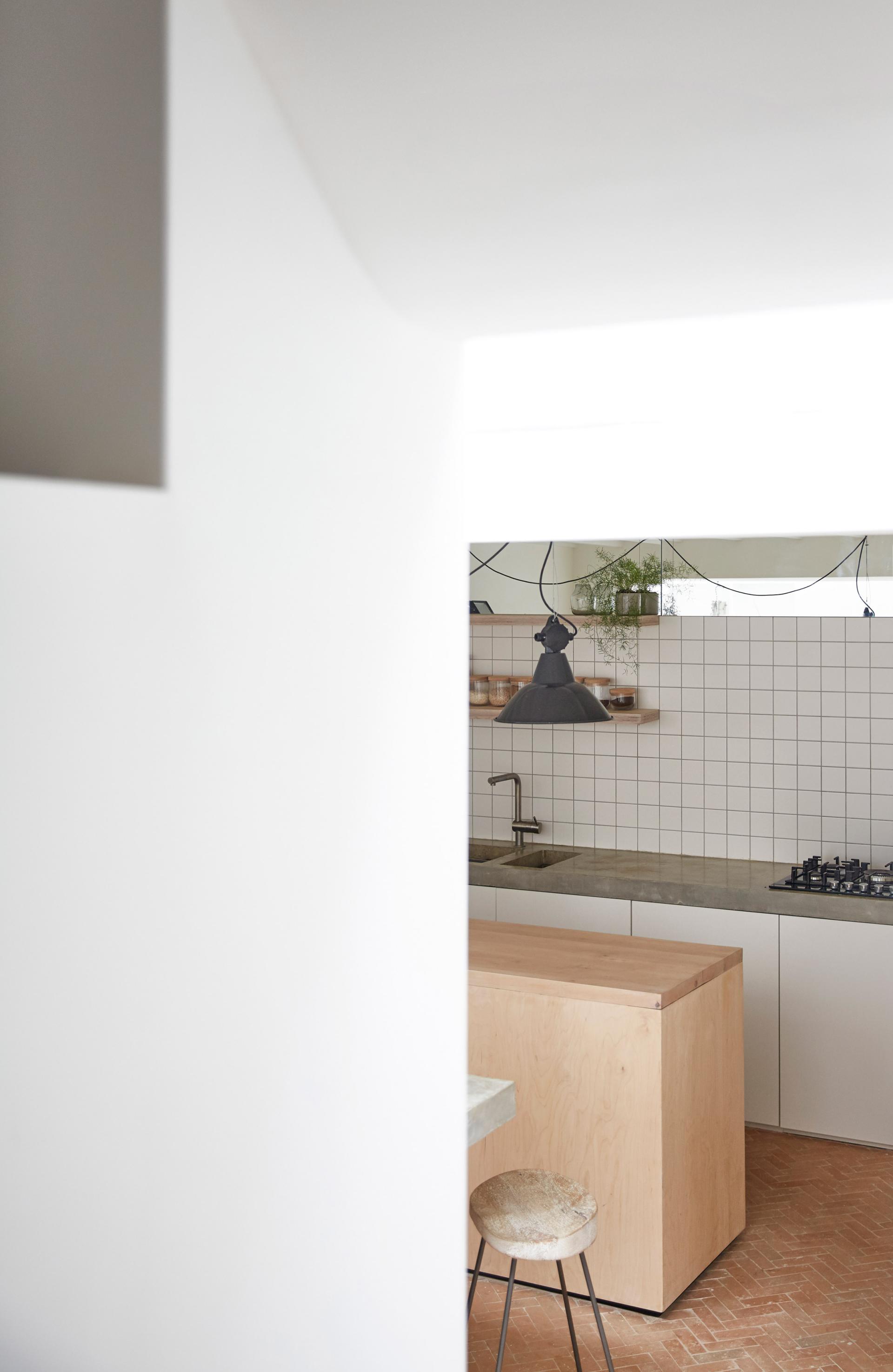Modern kitchen with plywood island and minimalist design, featuring white tiles and concrete countertop, designed by Hutch in Hackney.