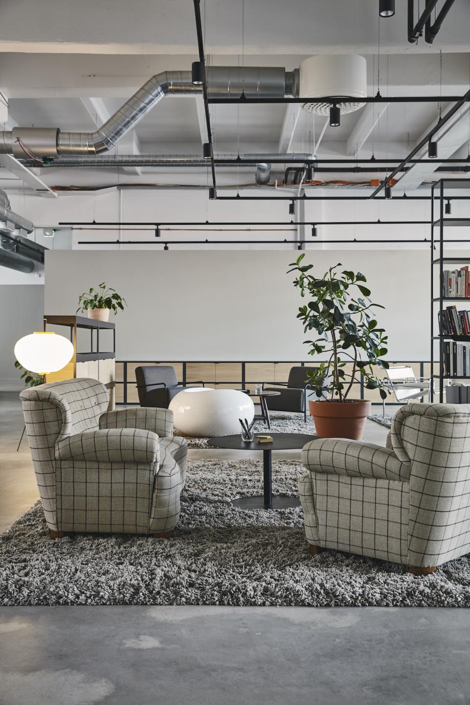 Stylish seating area featuring plaid armchairs, modern decor, and greenery in the renovated Bob the Robot workspace.