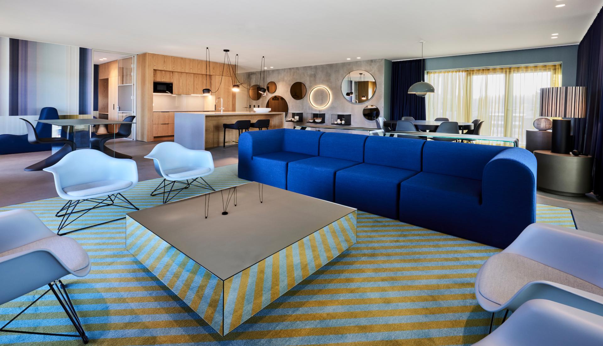 Vibrant living room in Kirk Suites, featuring Ege Carpets' colorful striped rug and modern furnishings in Vejle, Denmark.