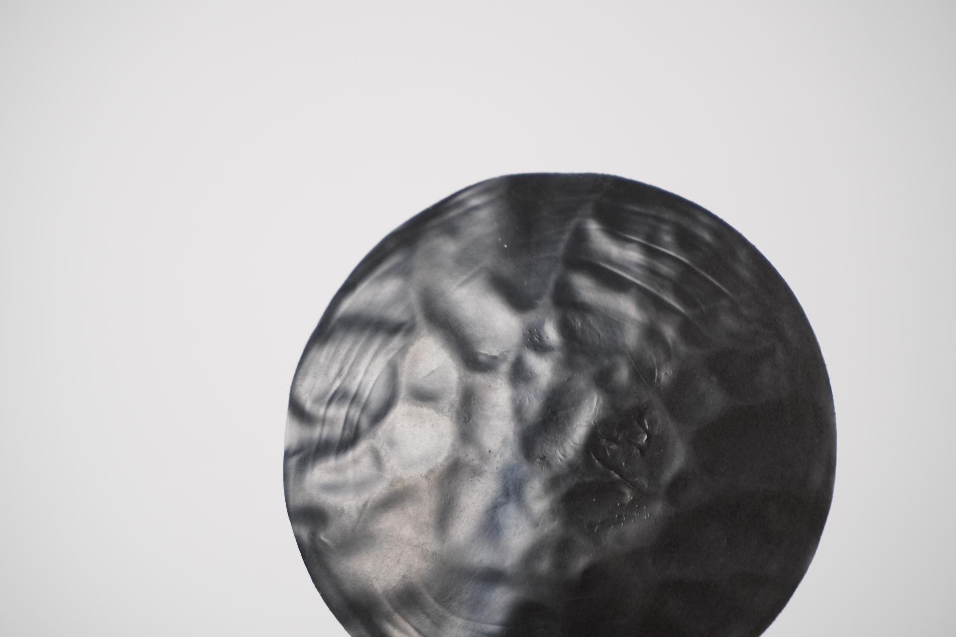 Textured black circular object representing innovative biomaterials in sustainable practices featured in Bioforcetech's exhibition.