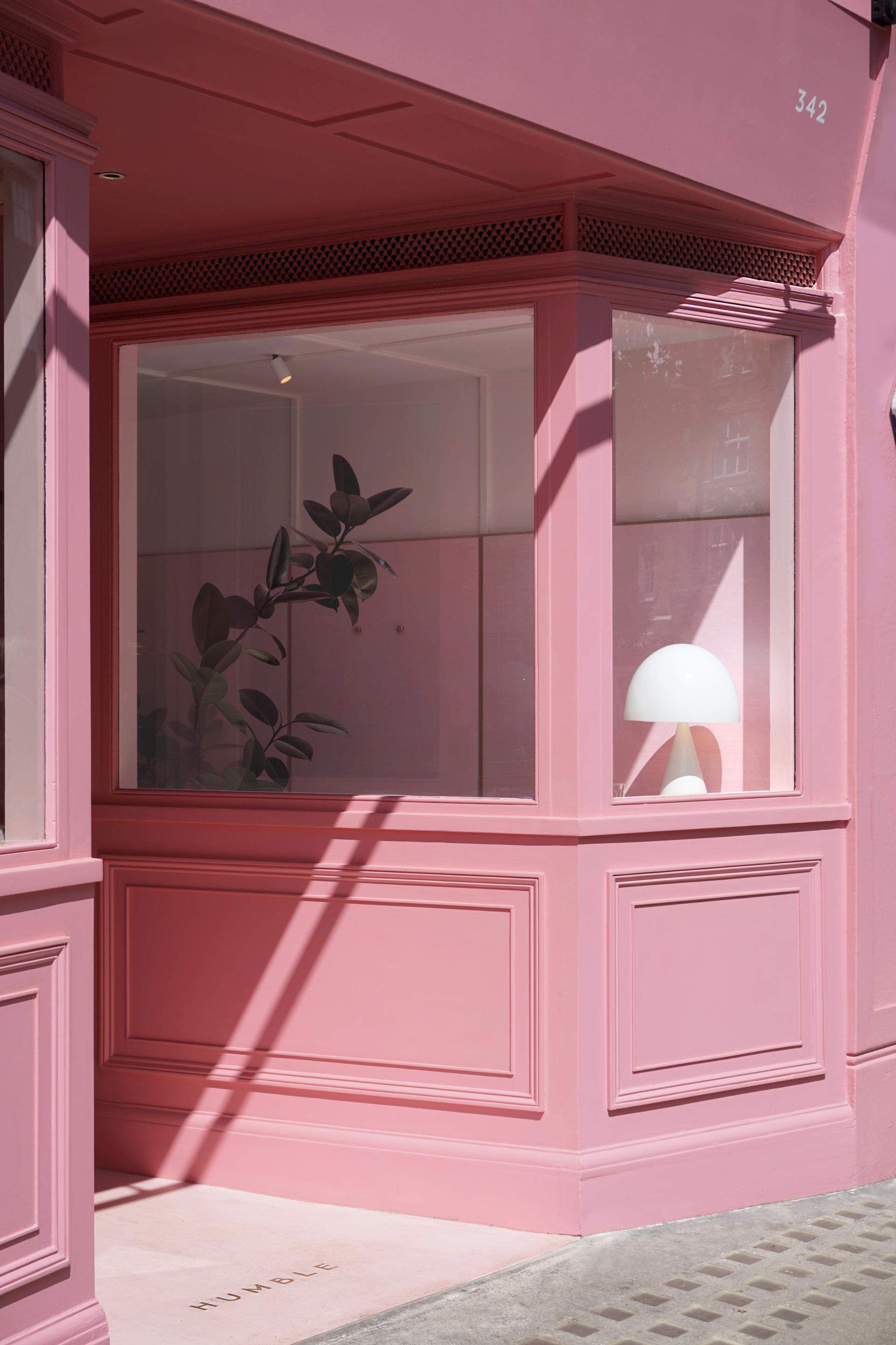 Charming dusky-pink café exterior with stylish decor, featuring a plant and minimalist lamp, on King's Road.