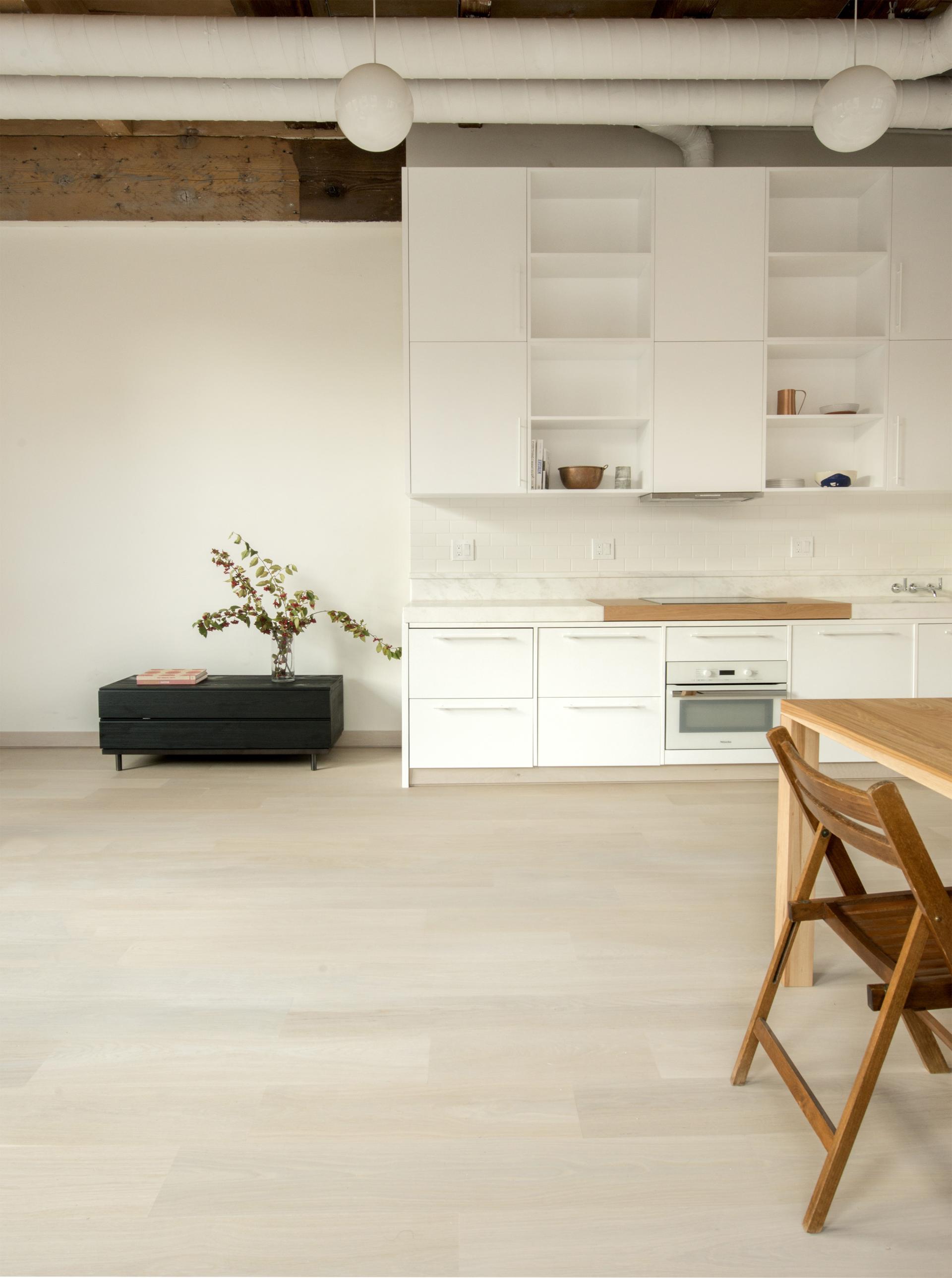 Modern kitchen design featuring white cabinetry, a wooden dining table, and a black TV stand in Pioneer Square, Seattle.