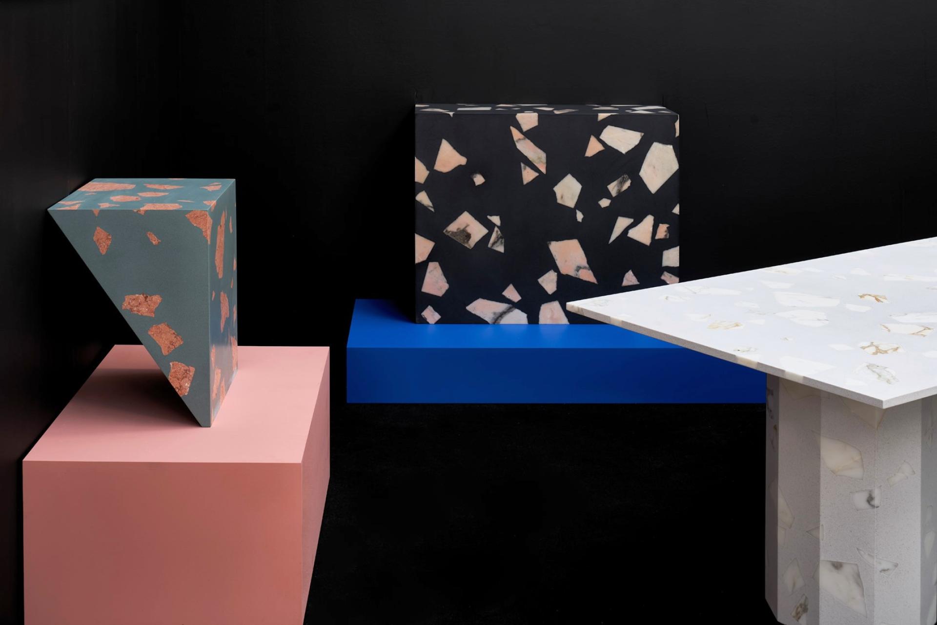 Colorful terrazzo furniture pieces, including a table and geometric shapes, showcased against a black background.