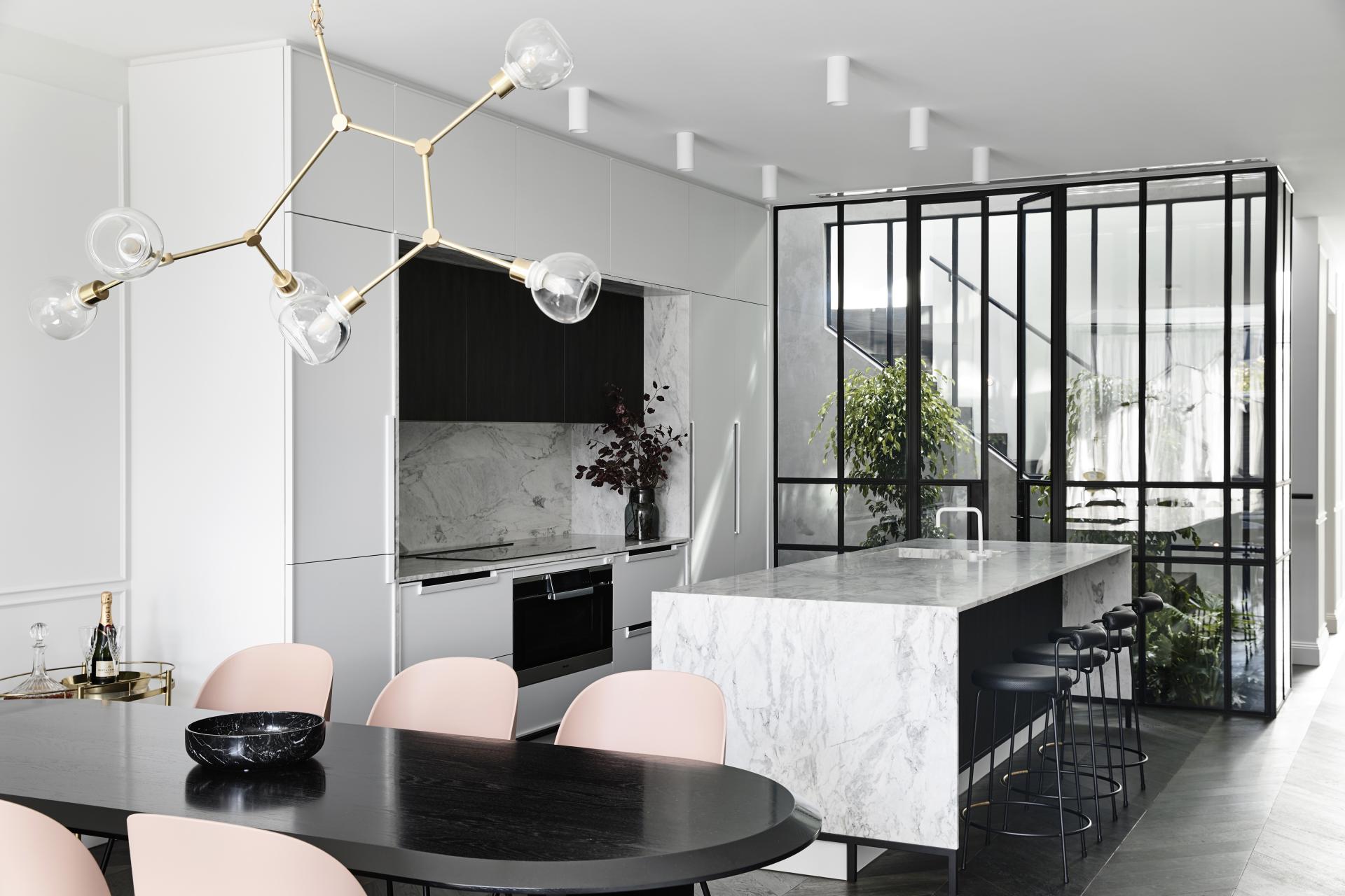 Modern kitchen design featuring sleek cabinetry, a marble island, and an elegant dining area with chic lighting.