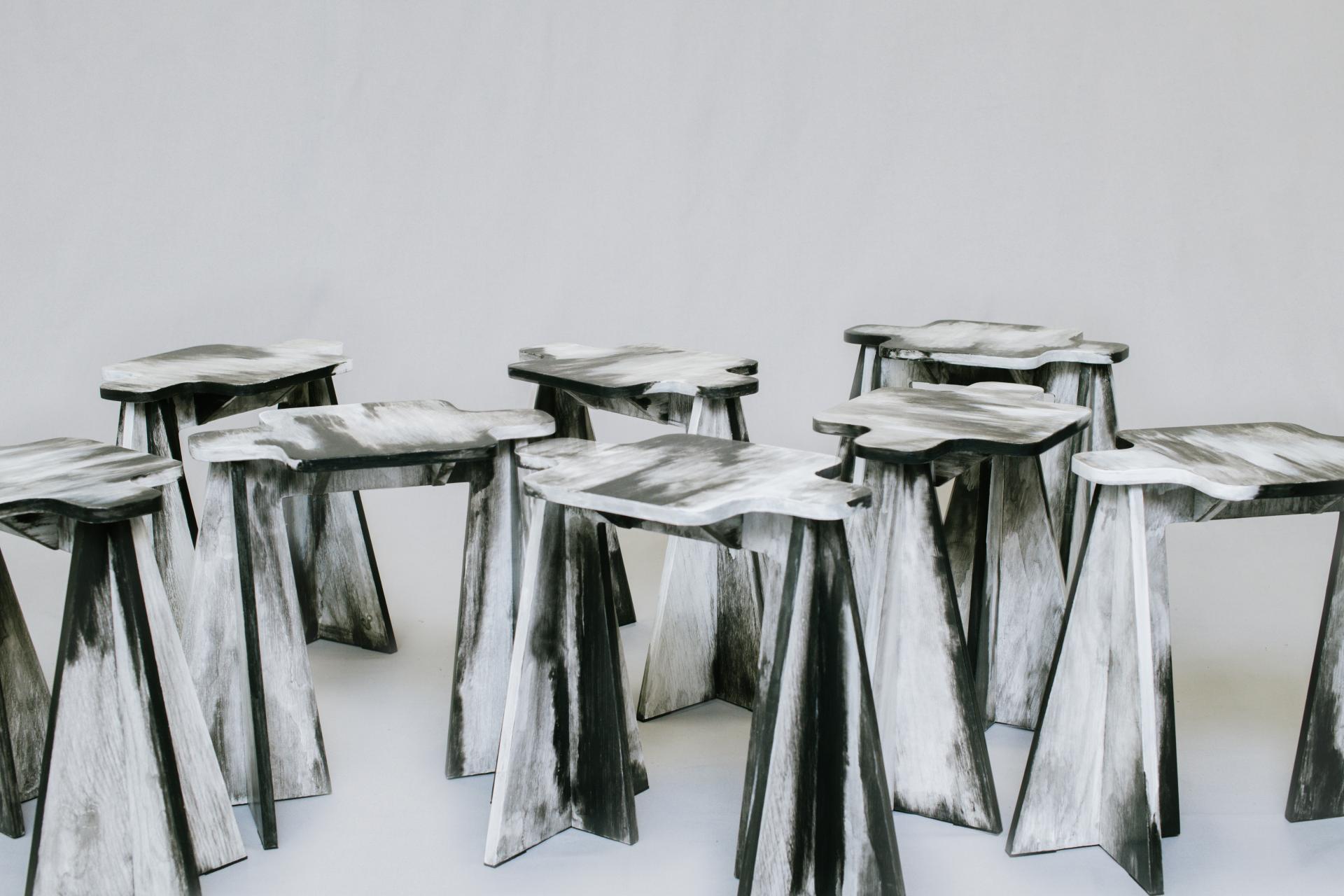 A collection of uniquely designed black and white wooden stools showcased at Adorno's Paris Design Week exhibition.