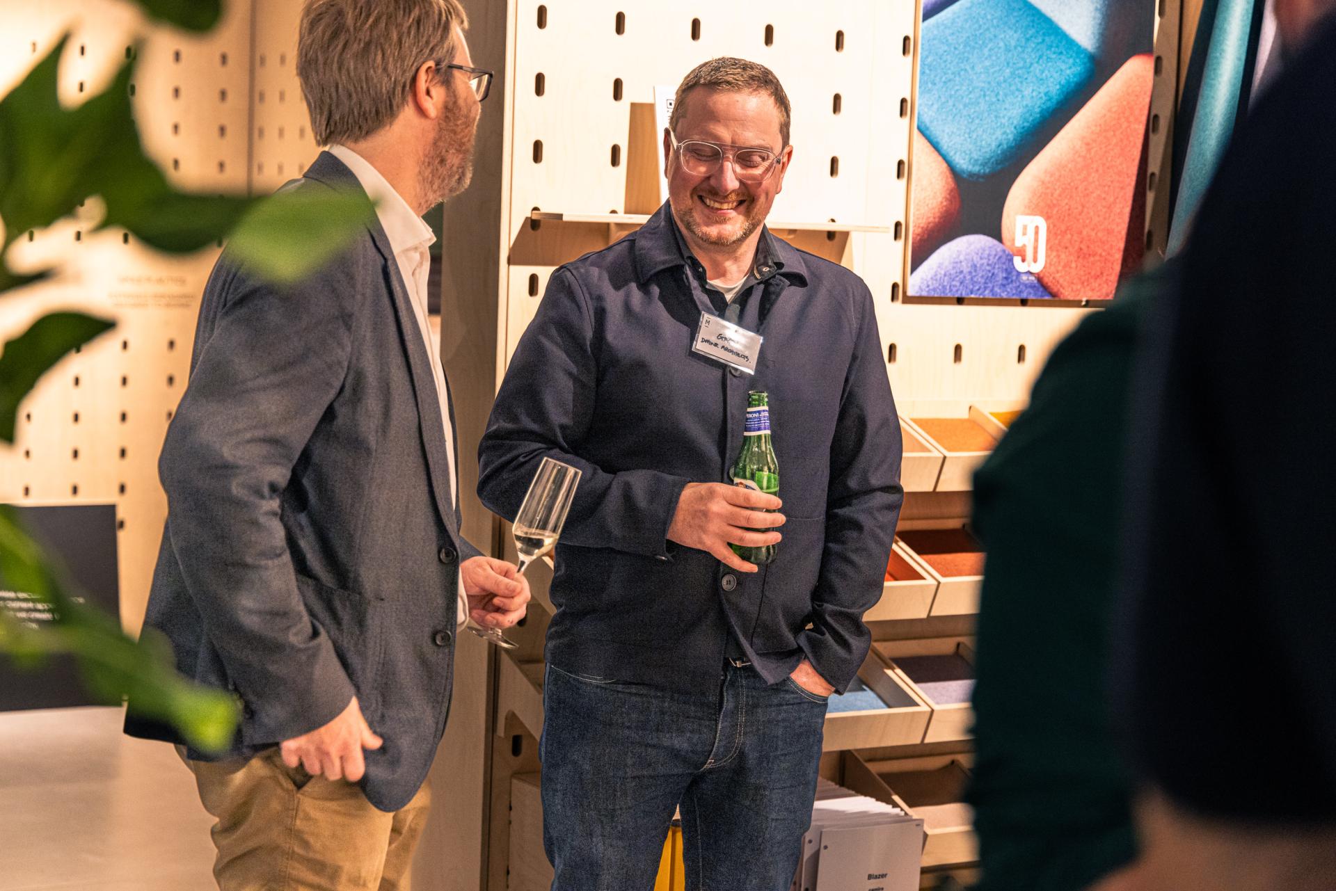 Two attendees engage in conversation at the Manchester Property Outlook seminar, surrounded by colorful material samples.