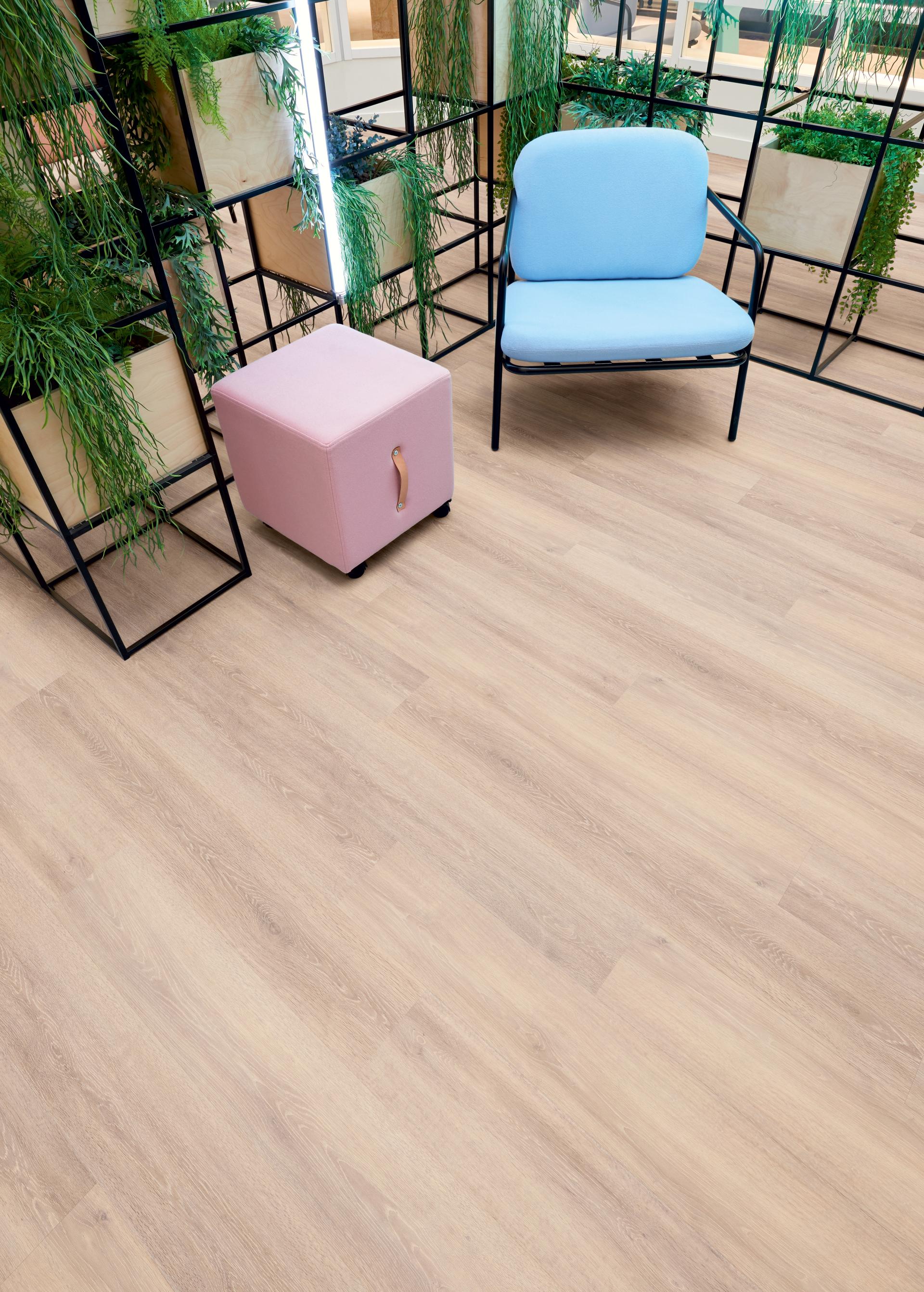 Spacia Luxury Vinyl Tile flooring showcased in a modern interior with greenery, a pink ottoman, and a blue chair.