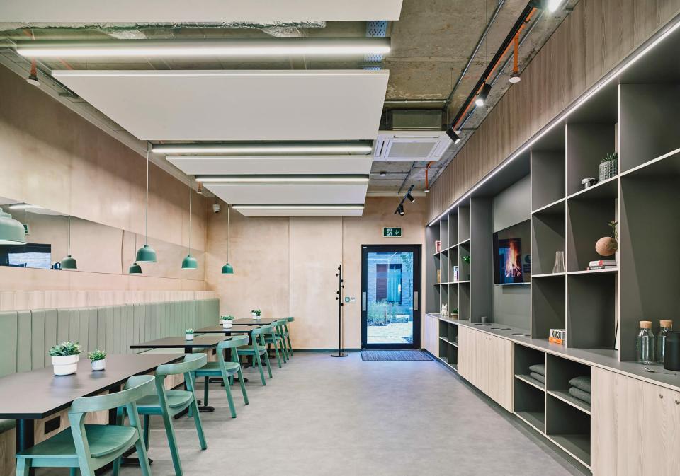 Modern student lounge in The Tannery, Leicester, featuring green chairs, tables, and contemporary decor.