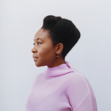 Natsai Audrey Chieza, a materials designer, poses in a pink sweater, highlighting biodesign and sustainability themes.