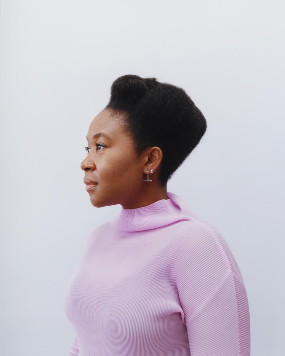 Natsai Audrey Chieza, a materials designer, poses in a pink sweater, highlighting biodesign and sustainability themes.