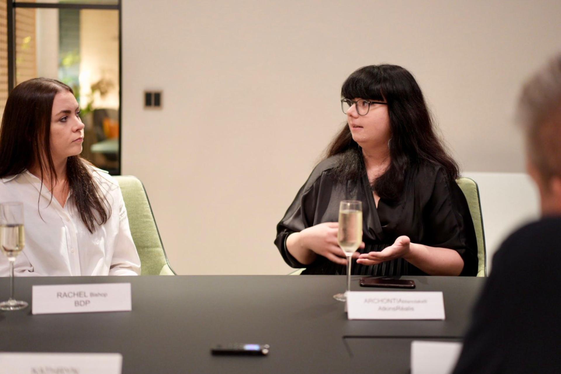 Two women engaged in a discussion during a workplace meeting, emphasizing collaboration and communication in modern work environments.