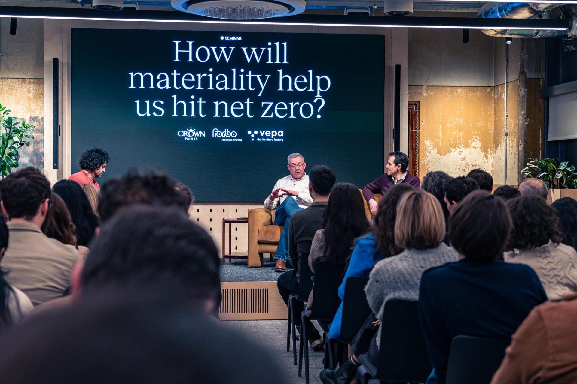 Panel discussion on materiality's role in achieving Net Zero, featuring speakers in a seminar setting.