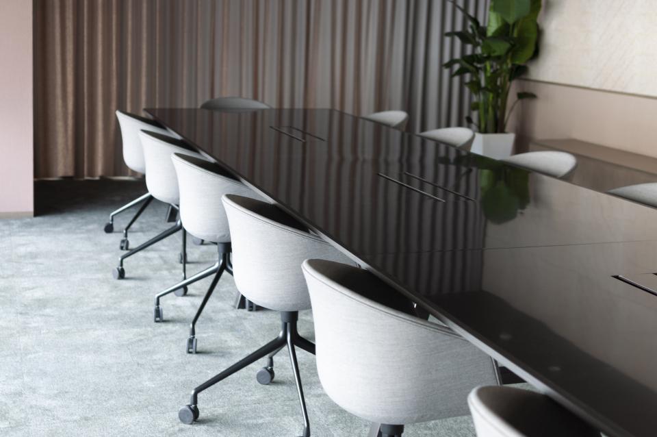 Modern conference room designed by Bean Buro for Warner Music Hong Kong, featuring a sleek black table and stylish chairs.