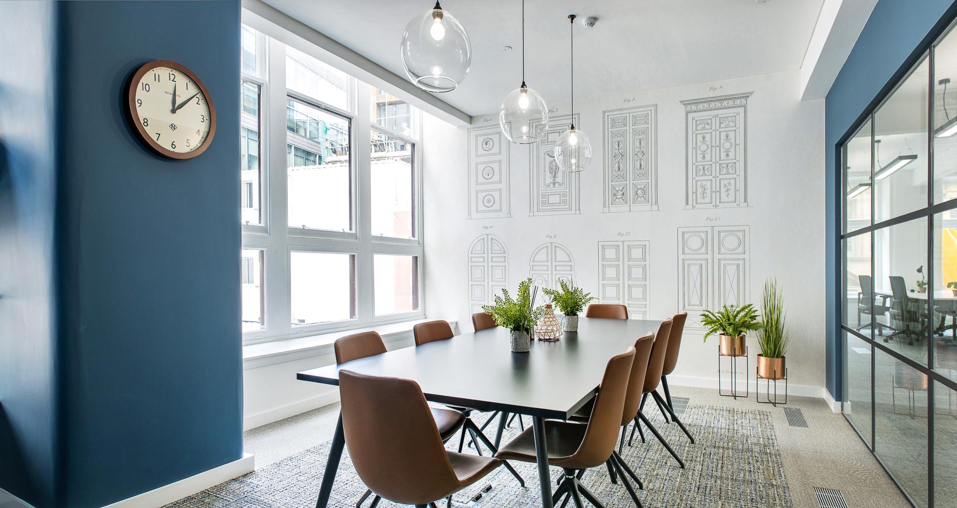 Modern conference room with a large table, stylish chairs, wall art, and natural light, showcasing Standing Space's design expertise.