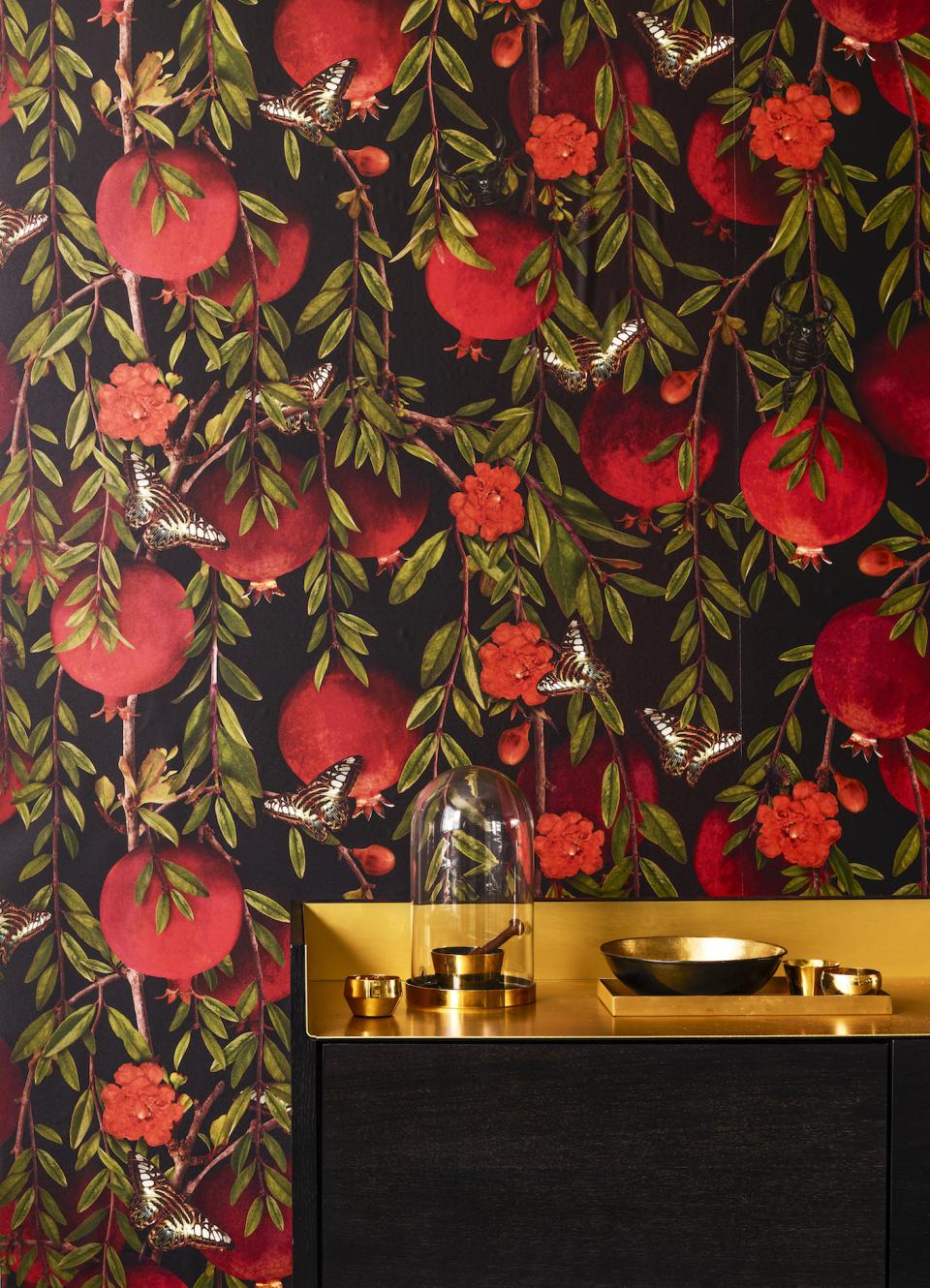 Dramatic floral wallpaper featuring red pomegranates, butterflies, and vibrant blooms, complementing a chic black and gold décor.