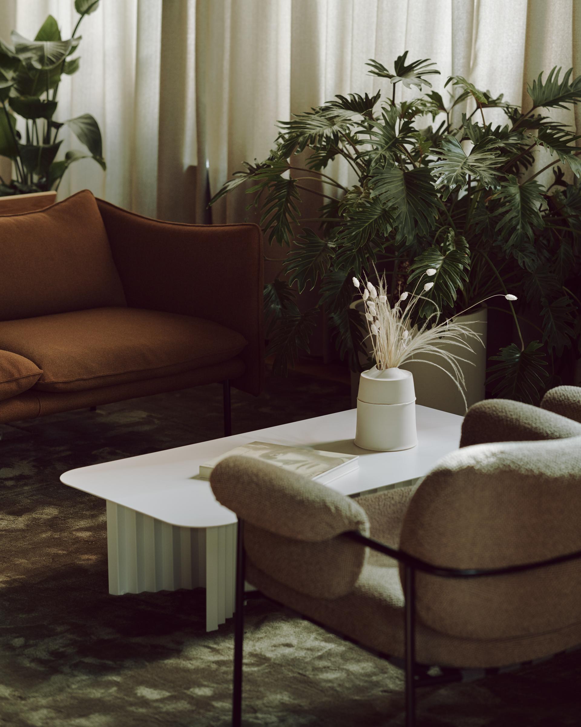 Stylish seating area in Summit House, featuring cozy couches, decorative plants, and a minimalist coffee table.