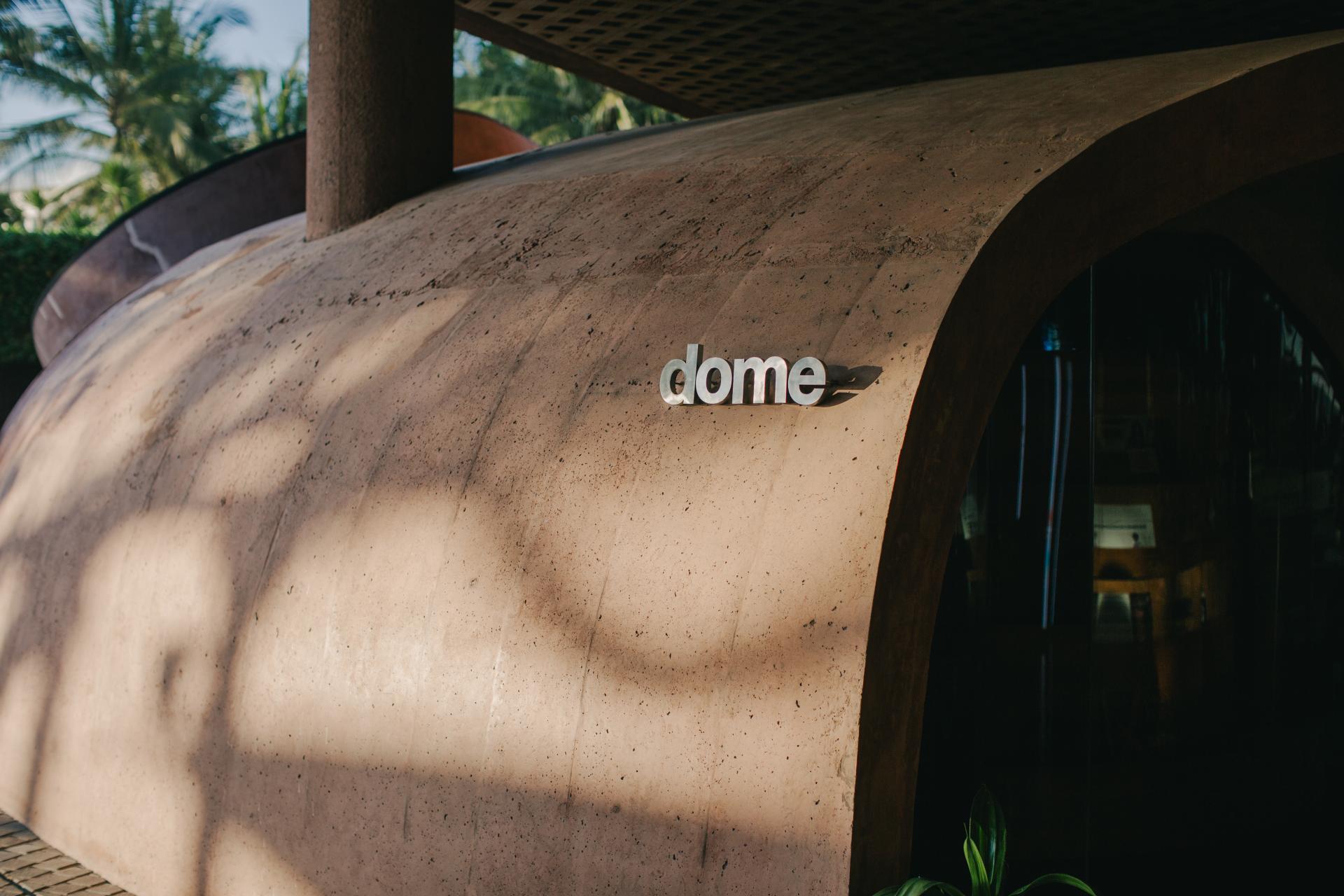 Sculptural earthy facade of Dome restaurant at Desa Potato Head, showcasing sustainable design with a modern aesthetic.