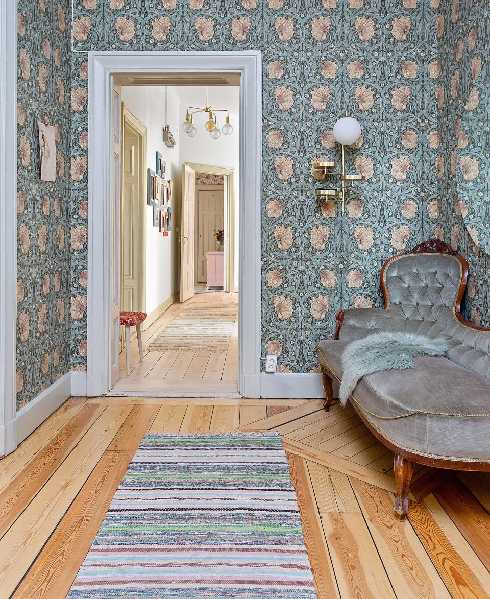 Charming Scandinavian interior featuring floral wallpaper, vintage couches, and wooden floors, reflecting Swedish design aesthetics.