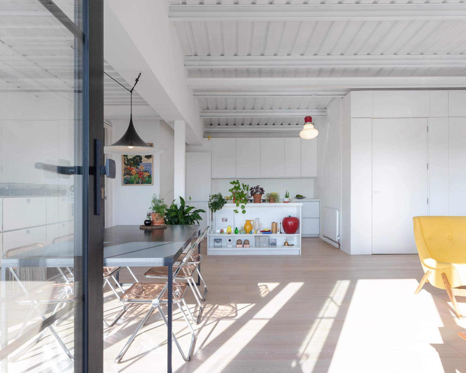 Bright and modern studio flat in a historic aircraft factory, featuring an open kitchen, dining area, and stylish decor.