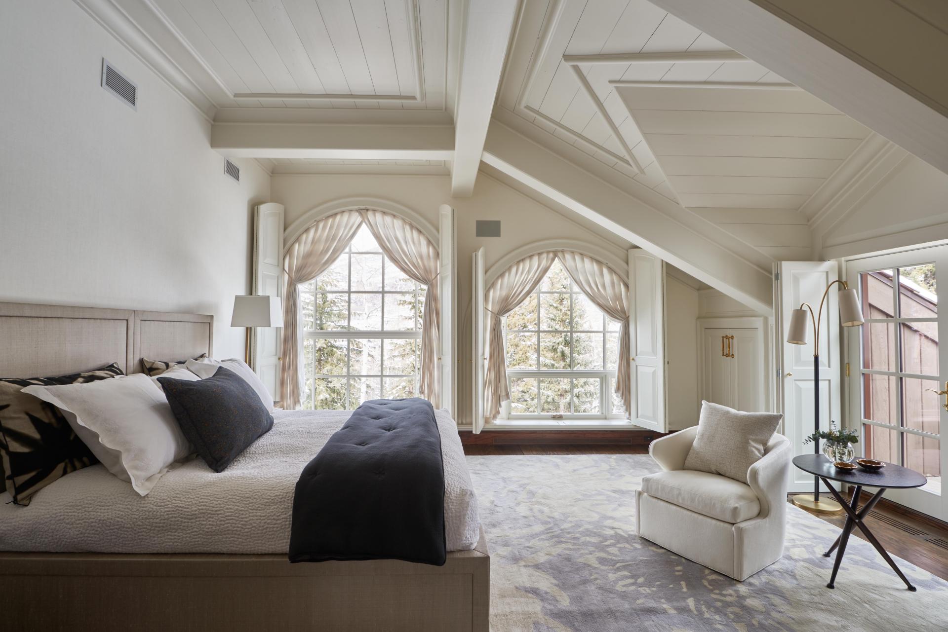Luxurious chalet bedroom featuring elegant decor, large windows, and a cozy sitting area, designed by Champalimaud Design.