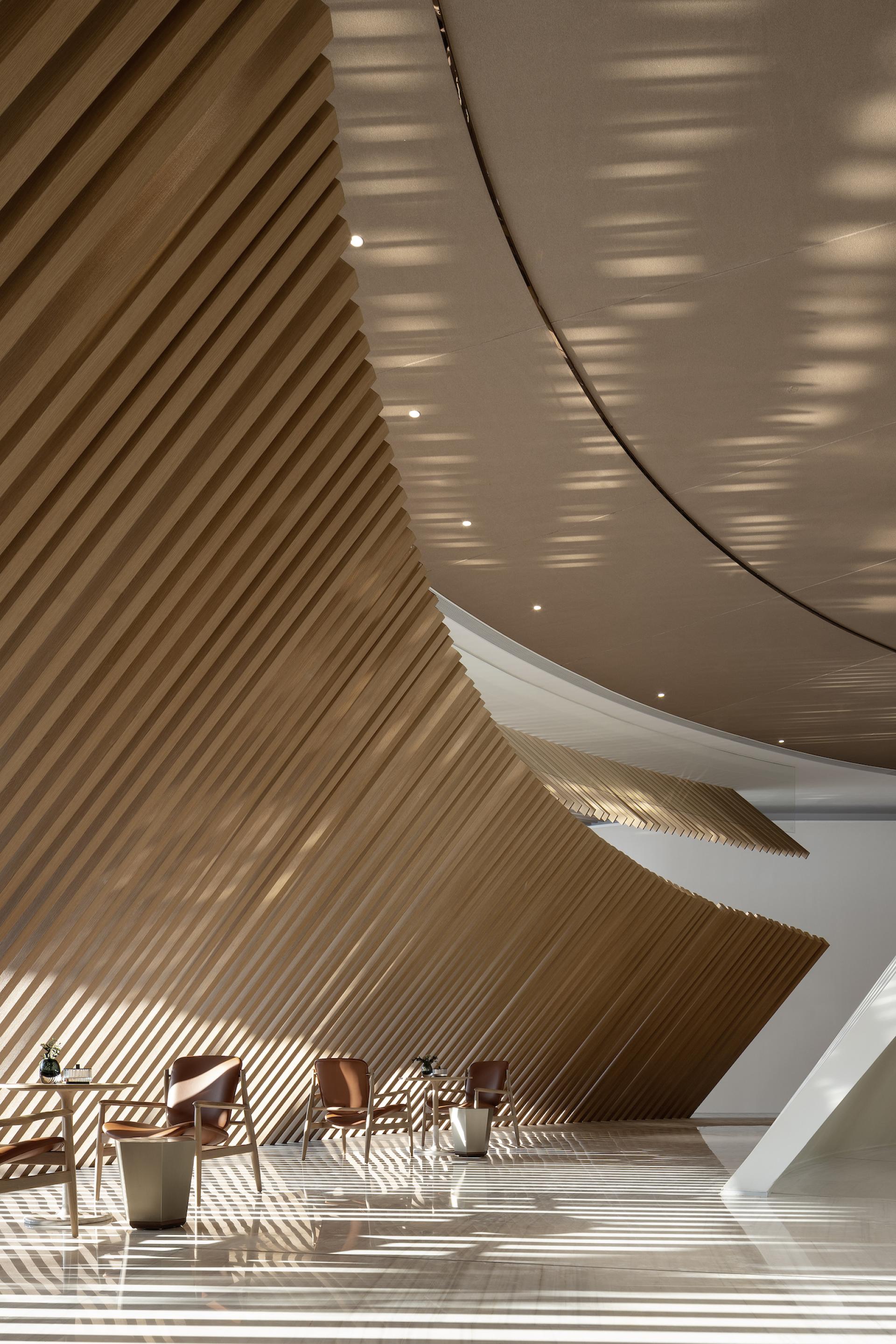 Interior view of The Florescence in Guangzhou, showcasing sweeping wooden curves and contemporary seating.