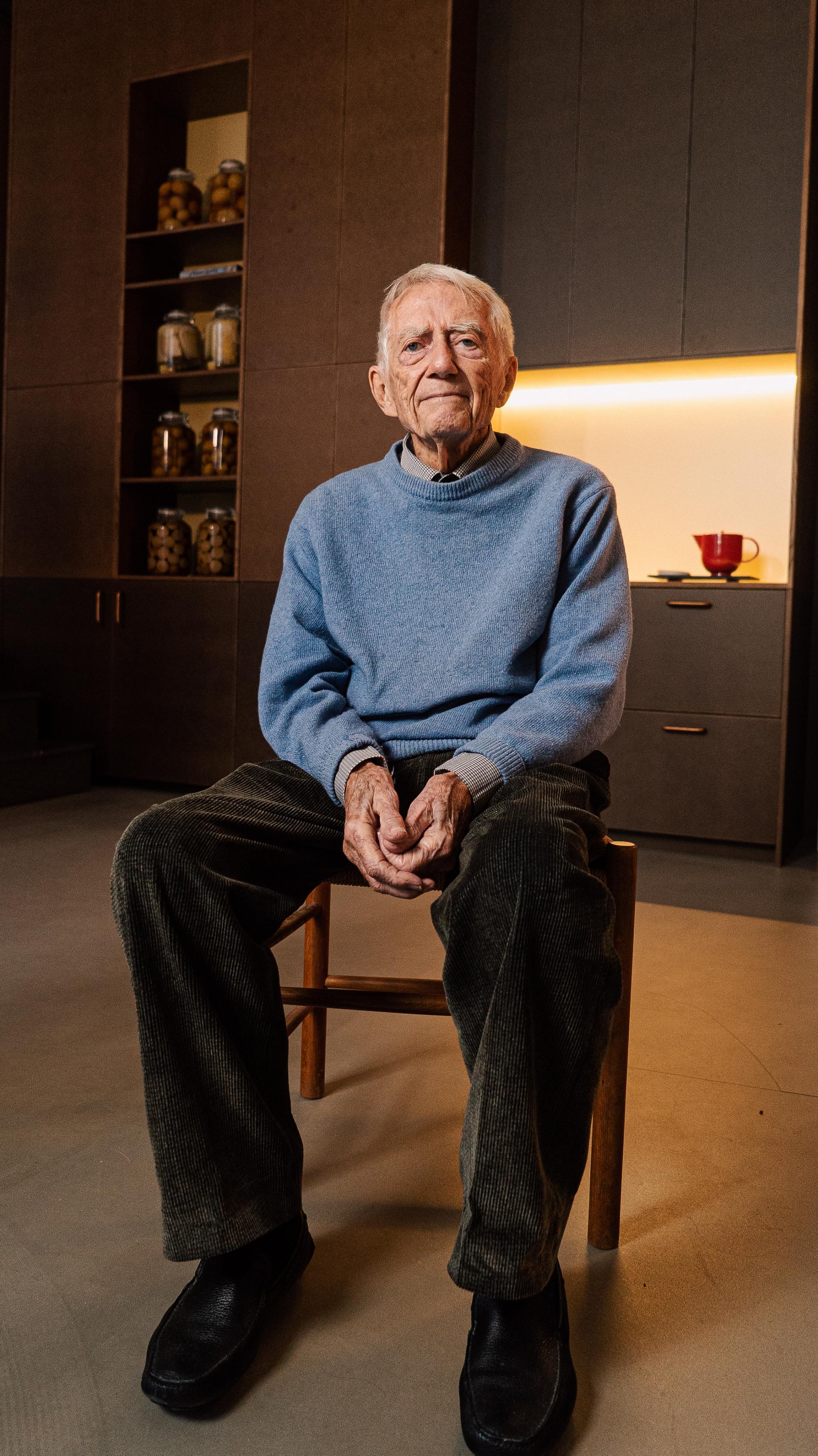 An elderly man sitting on a wooden chair in a modern kitchen showcasing d line's future-proof pull-handles.