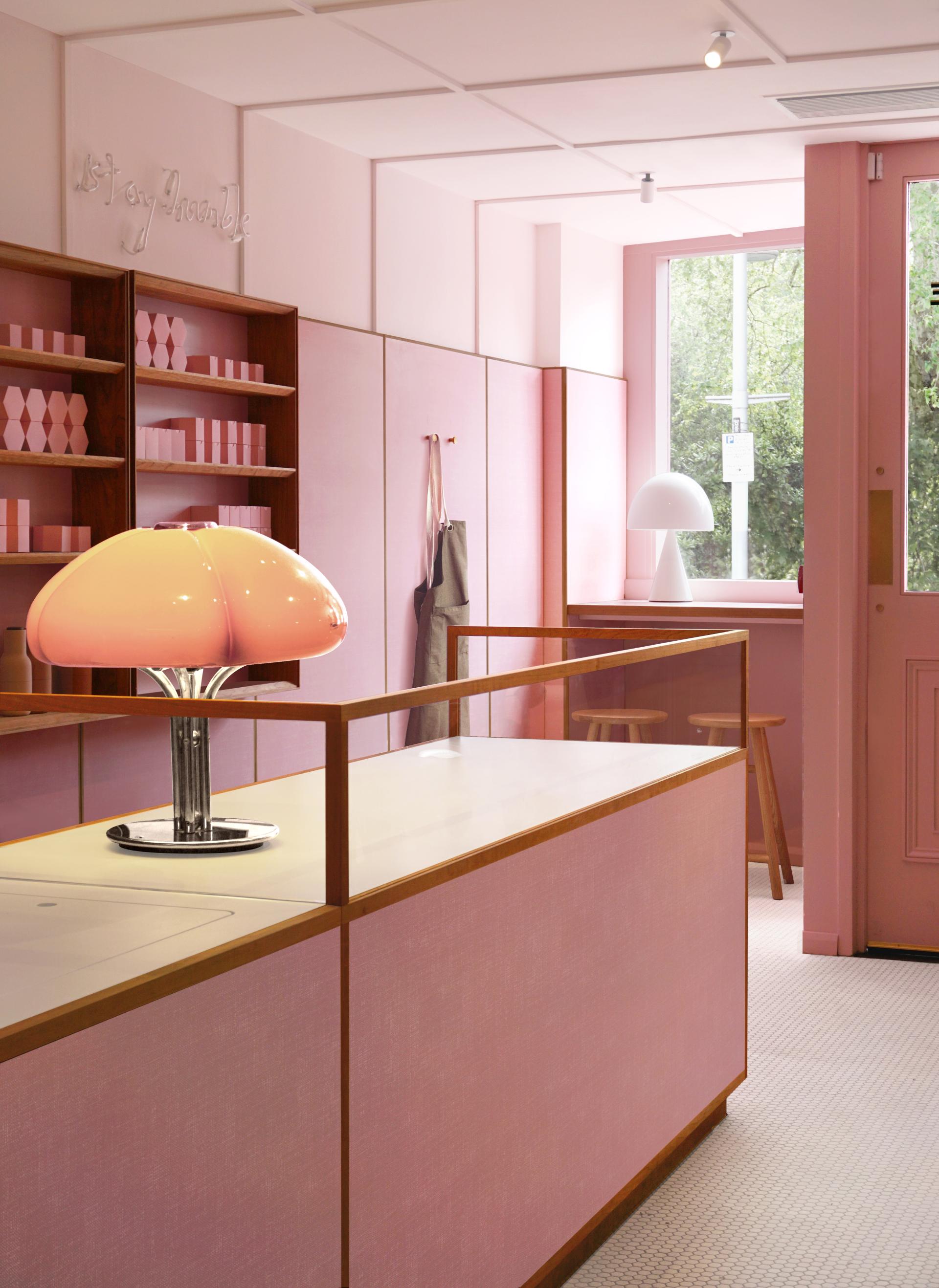 Stylish dusky-pink café interior featuring Formica® laminate surfaces, retro lighting, and minimalistic decor elements.