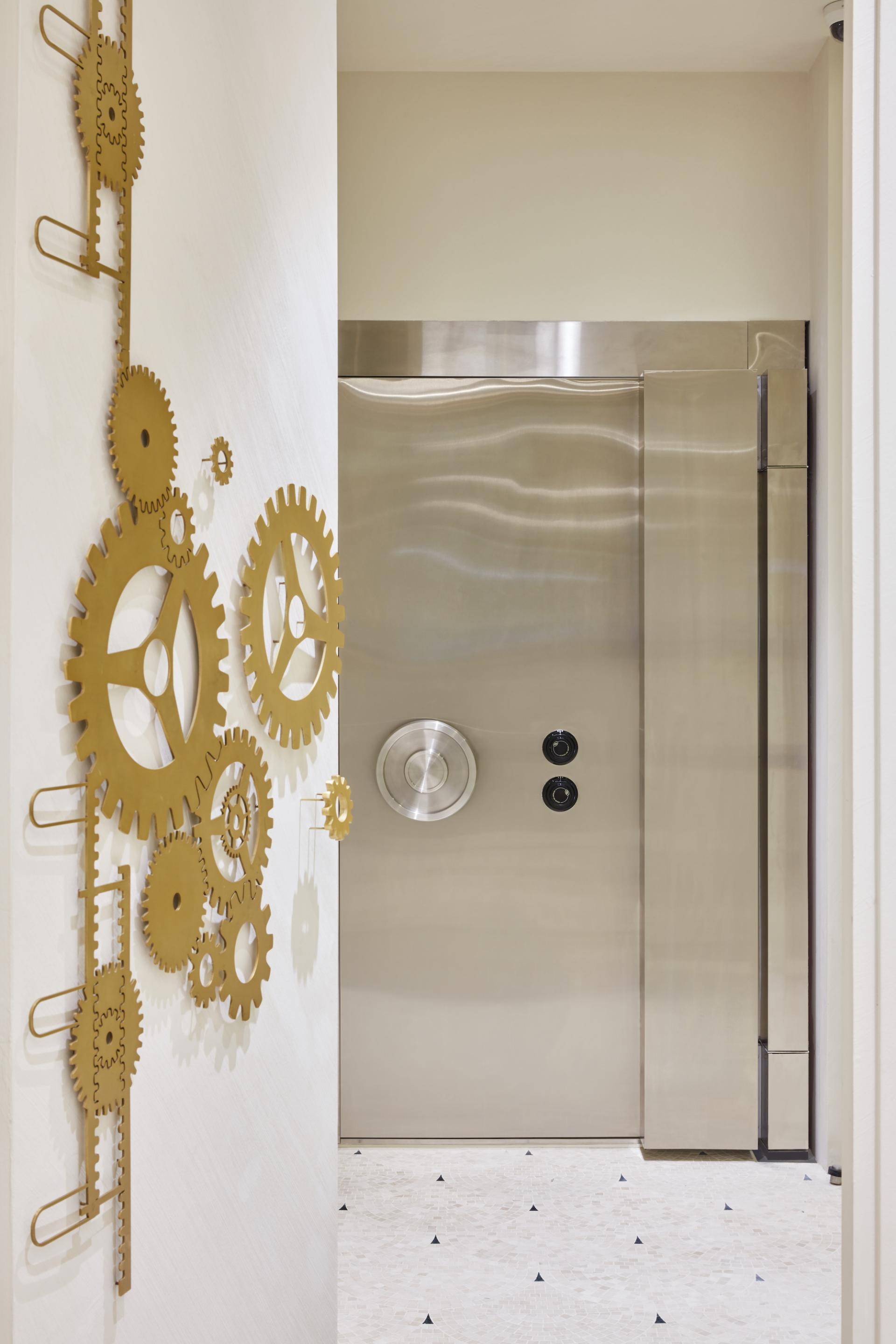 Modern interior design featuring an ornate metallic gear wall art next to a sleek metallic vault door in Dubai's Vintage Vaults.