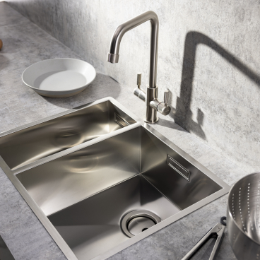 Stylish industrial kitchen sink with a 3 IN 1 hot tap, bowls, and kitchen utensils on a gray countertop.